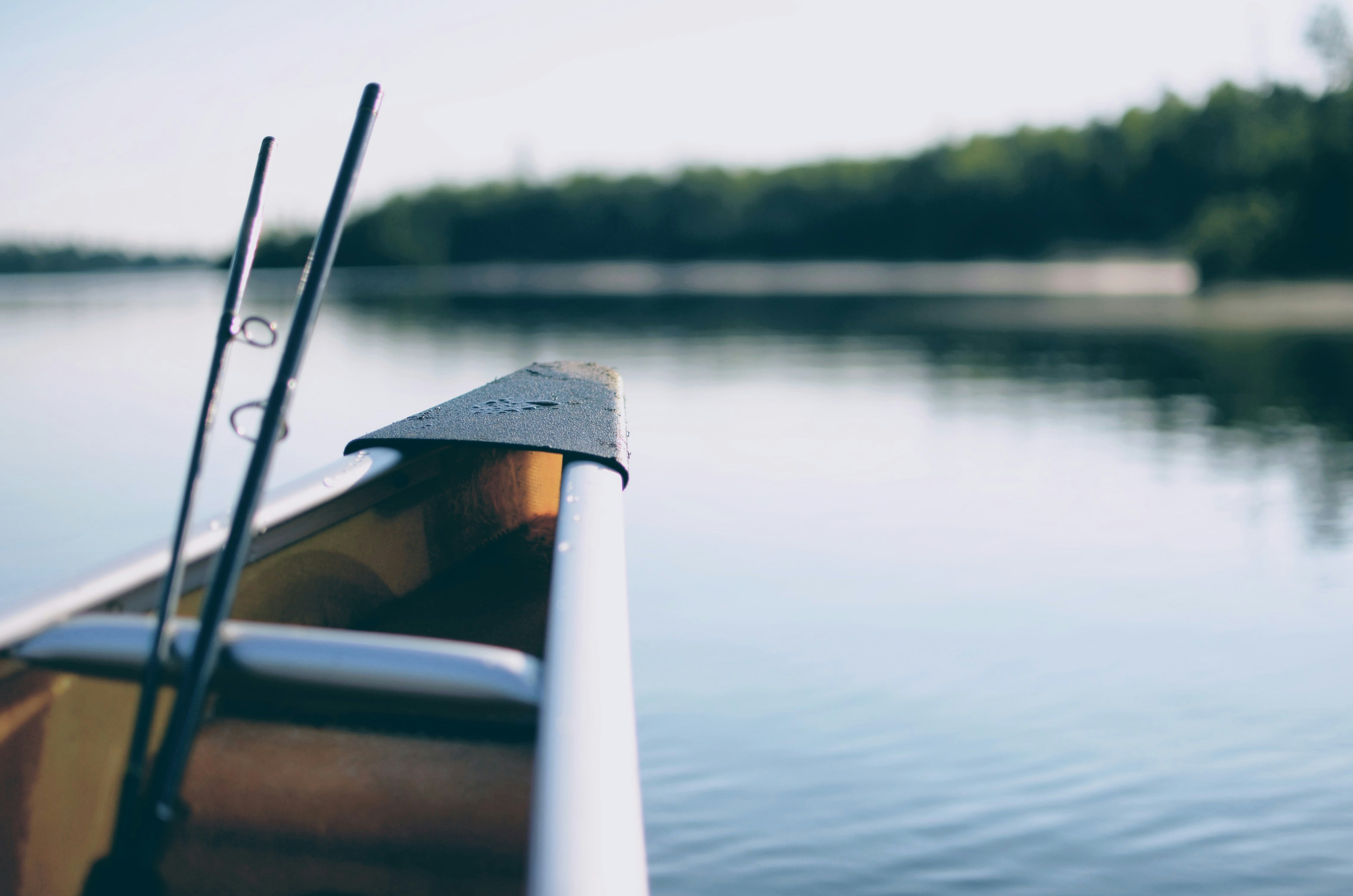 Canoe by a serene lake, ready for fishing with rods and peaceful reflections.