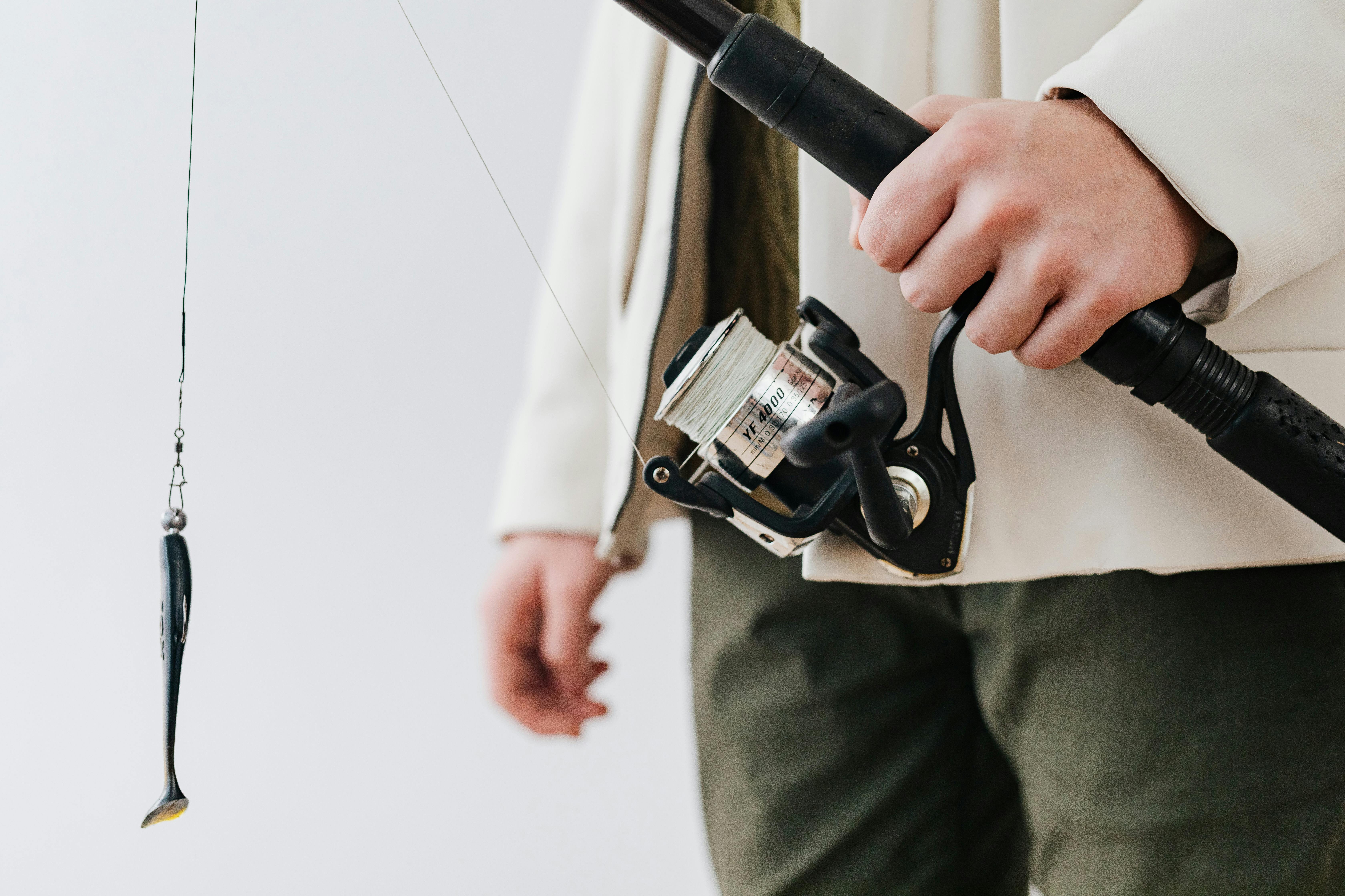 Fisherman prepares fishing gear with rod and spinning reel, ready for a fishing adventure.