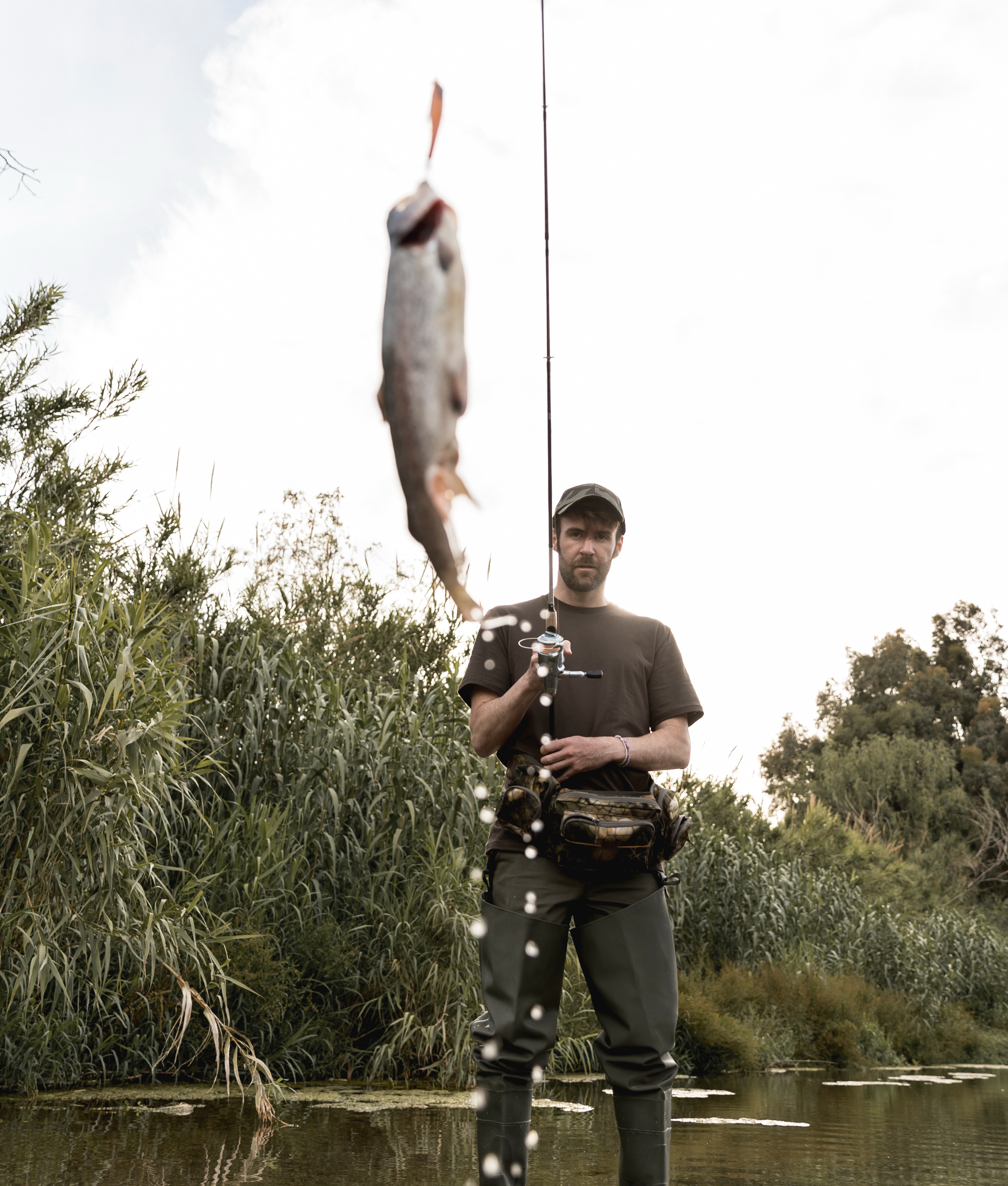 Successful fishing trip with a man reeling in a large fish at a serene lake.