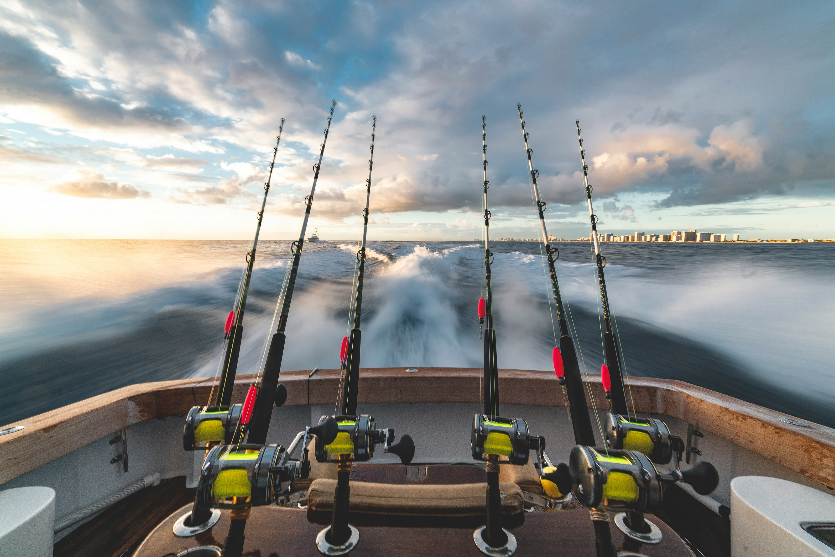 Fishing boat adventure with fishing rods, reels, and ocean scenery at sunset.