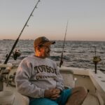 Relaxing fishing trip at twilight on a boat, featuring gear and a peaceful ocean view.