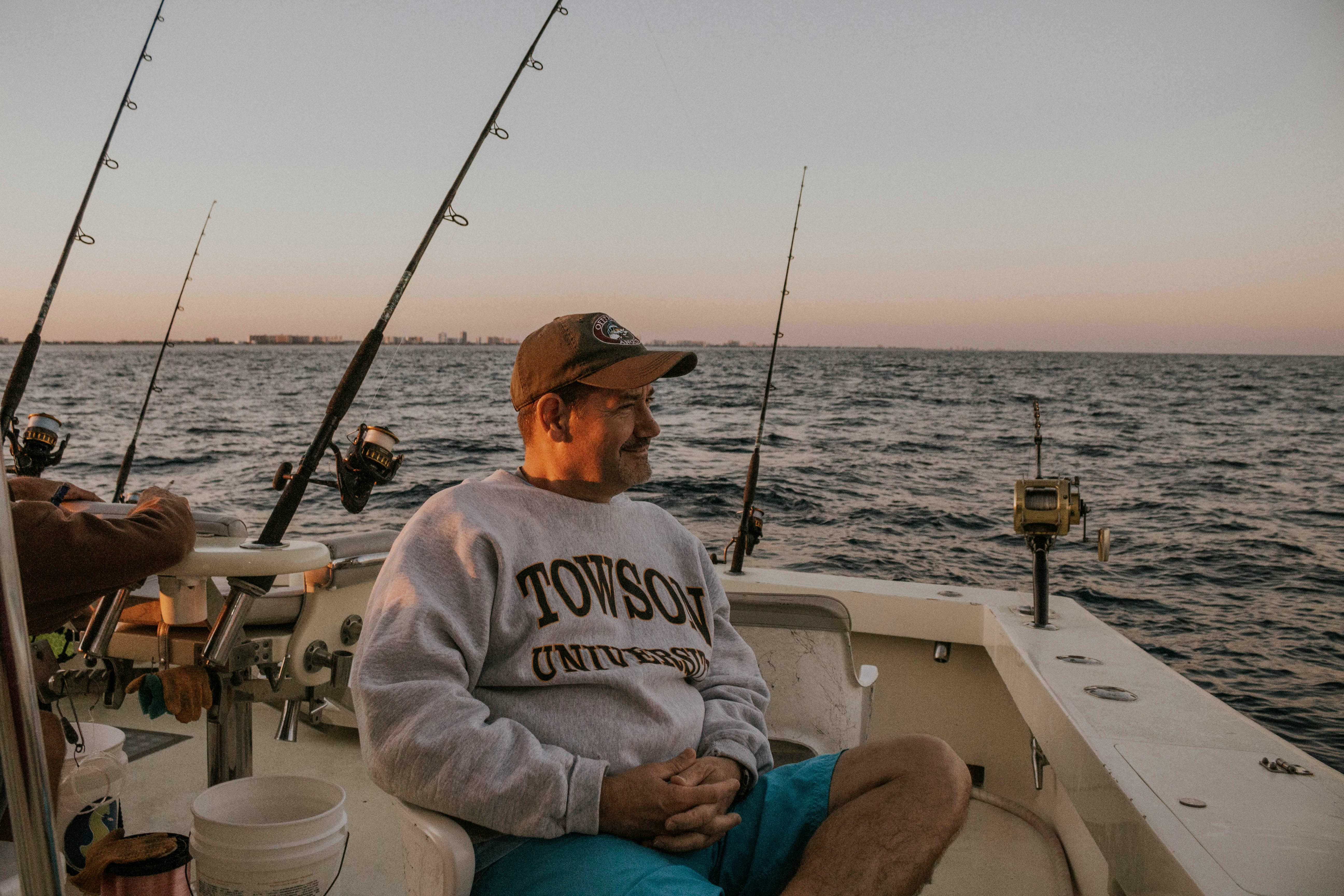 Relaxing fishing trip at twilight on a boat, featuring gear and a peaceful ocean view.