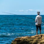 Angler fishing from a rocky shore, enjoying coastal serenity and beautiful ocean views.