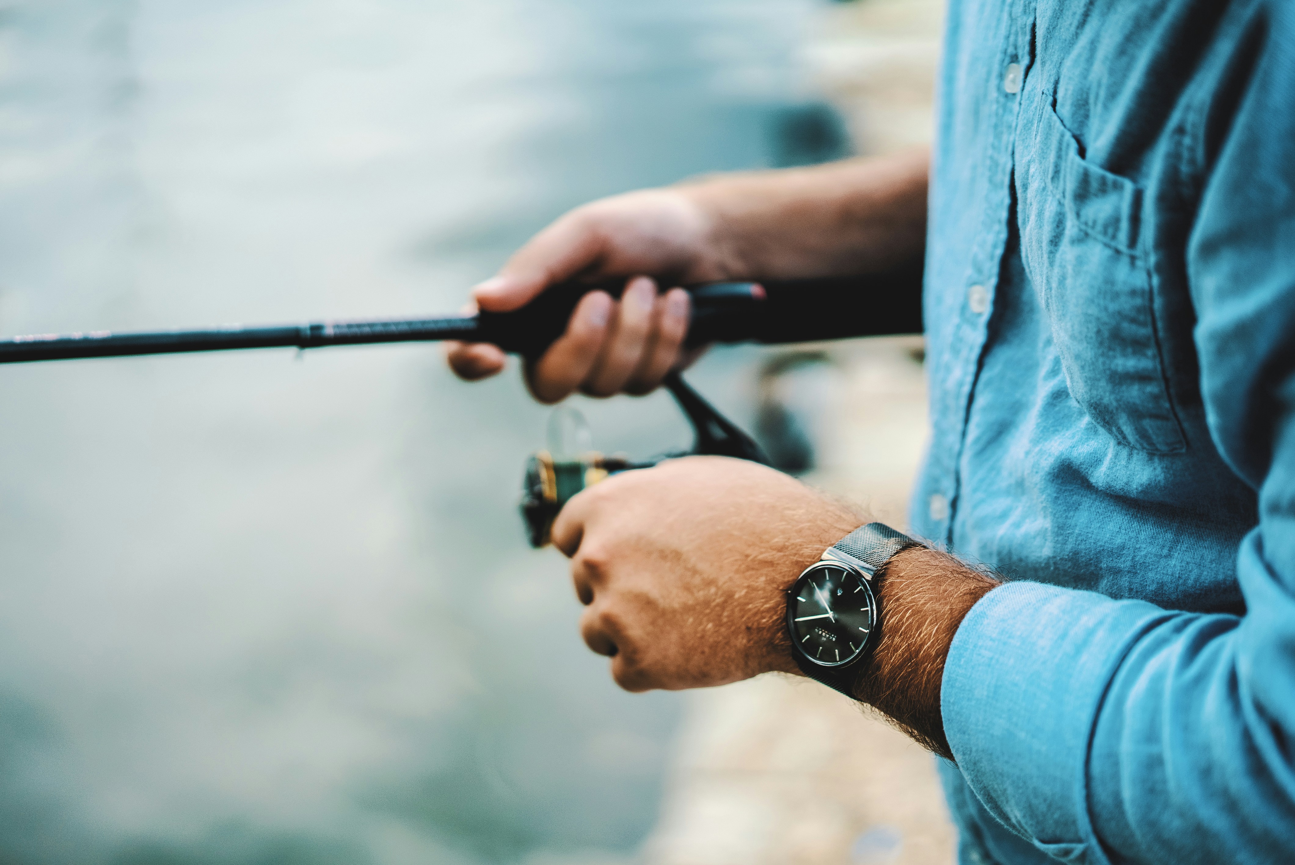 Person fishing by the water, showcasing quality fishing gear in a serene outdoor setting.