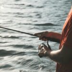 A man fishing in tranquil waters, showcasing fishing gear against a serene nature backdrop.