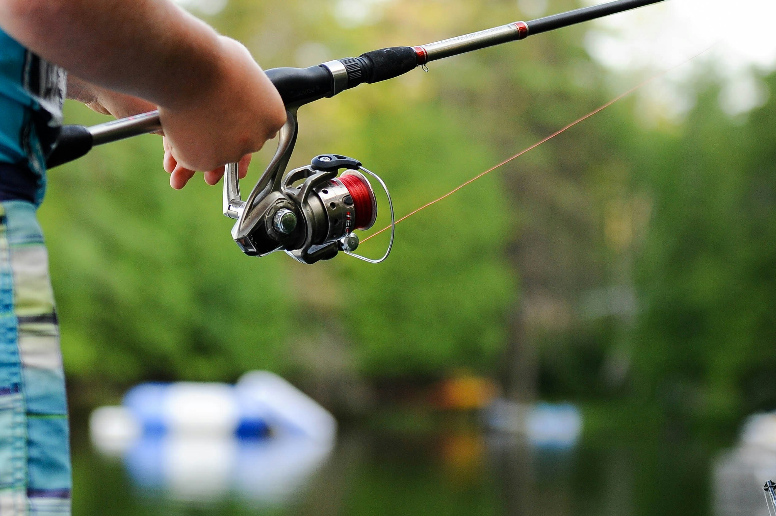 Serene fishing scene with modern rod, lush greenery, and tranquil water. Perfect outdoor escape.