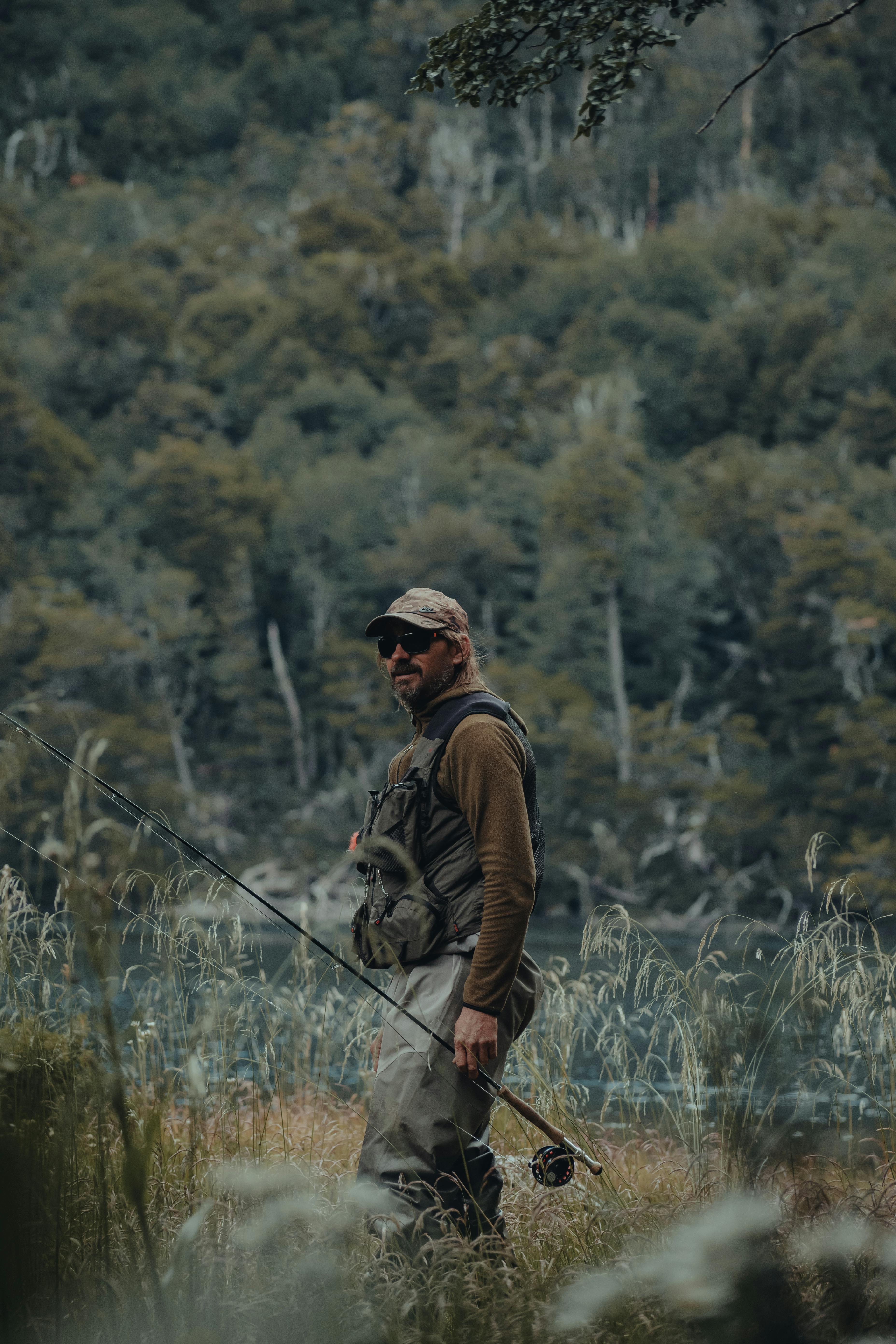 Man fishing peacefully by a serene water edge in lush green nature.