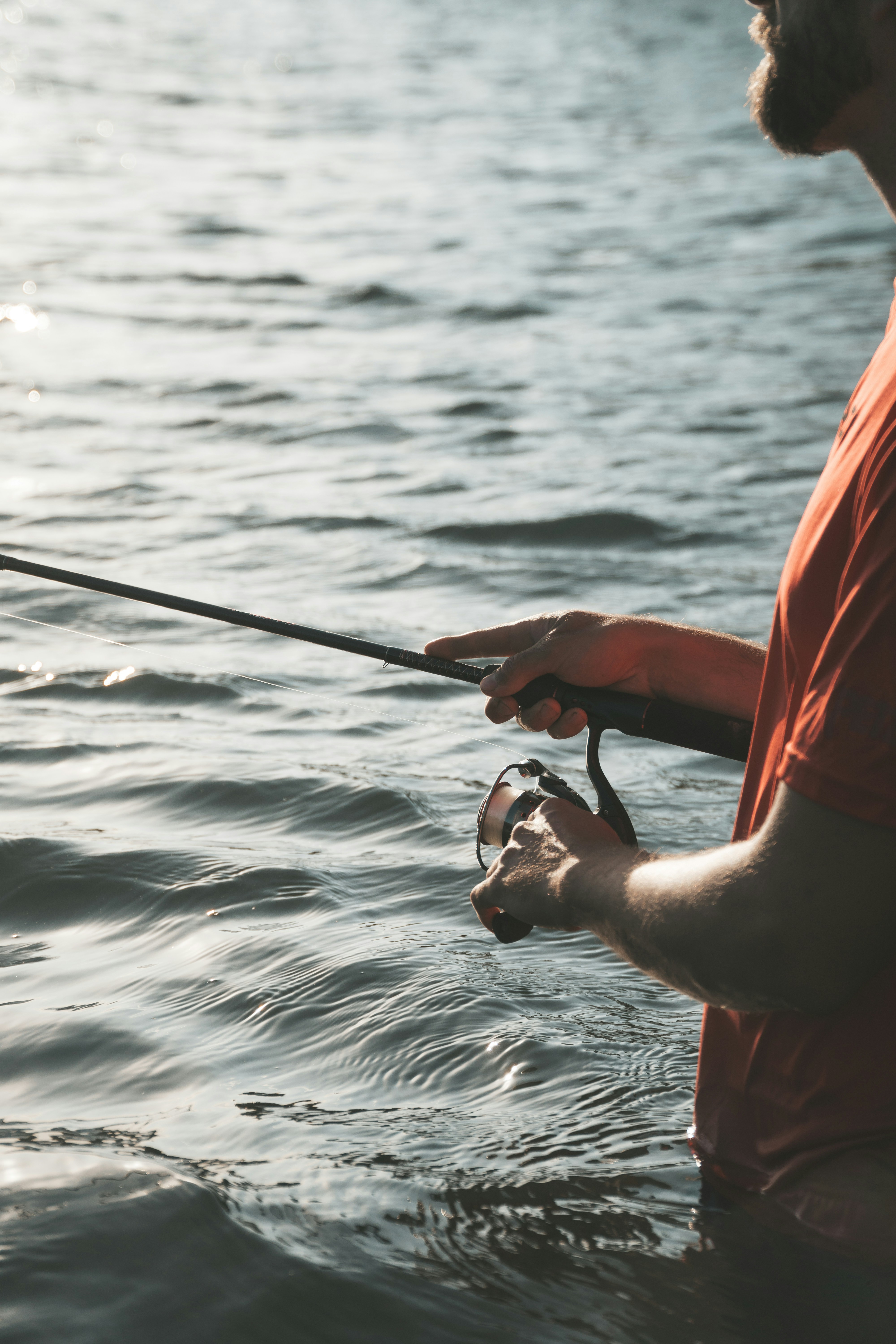 A man fishing in tranquil waters, showcasing fishing gear against a serene nature backdrop.