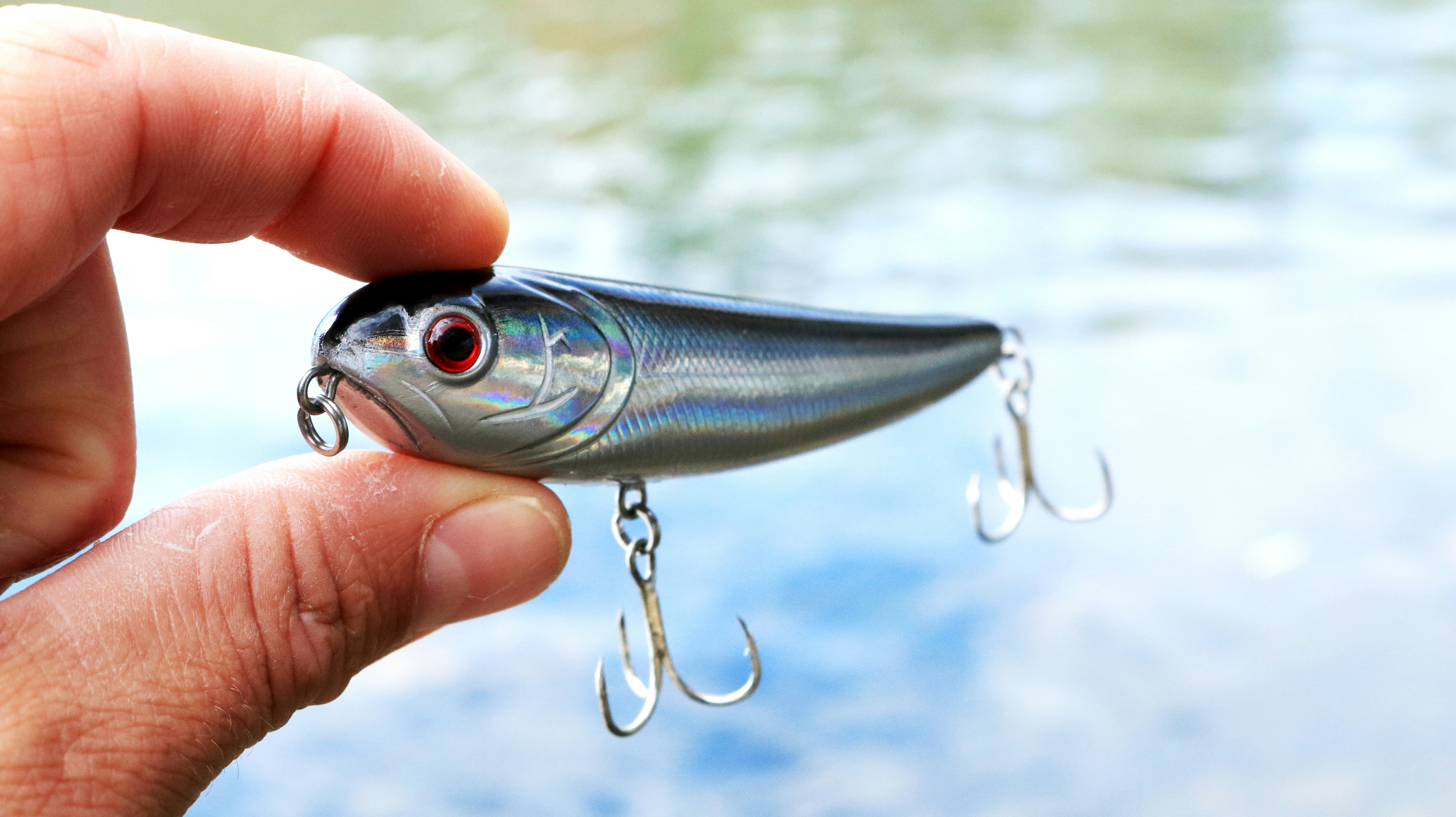 Close-up of a shiny, iridescent fishing lure held in hand, perfect for catching fish.