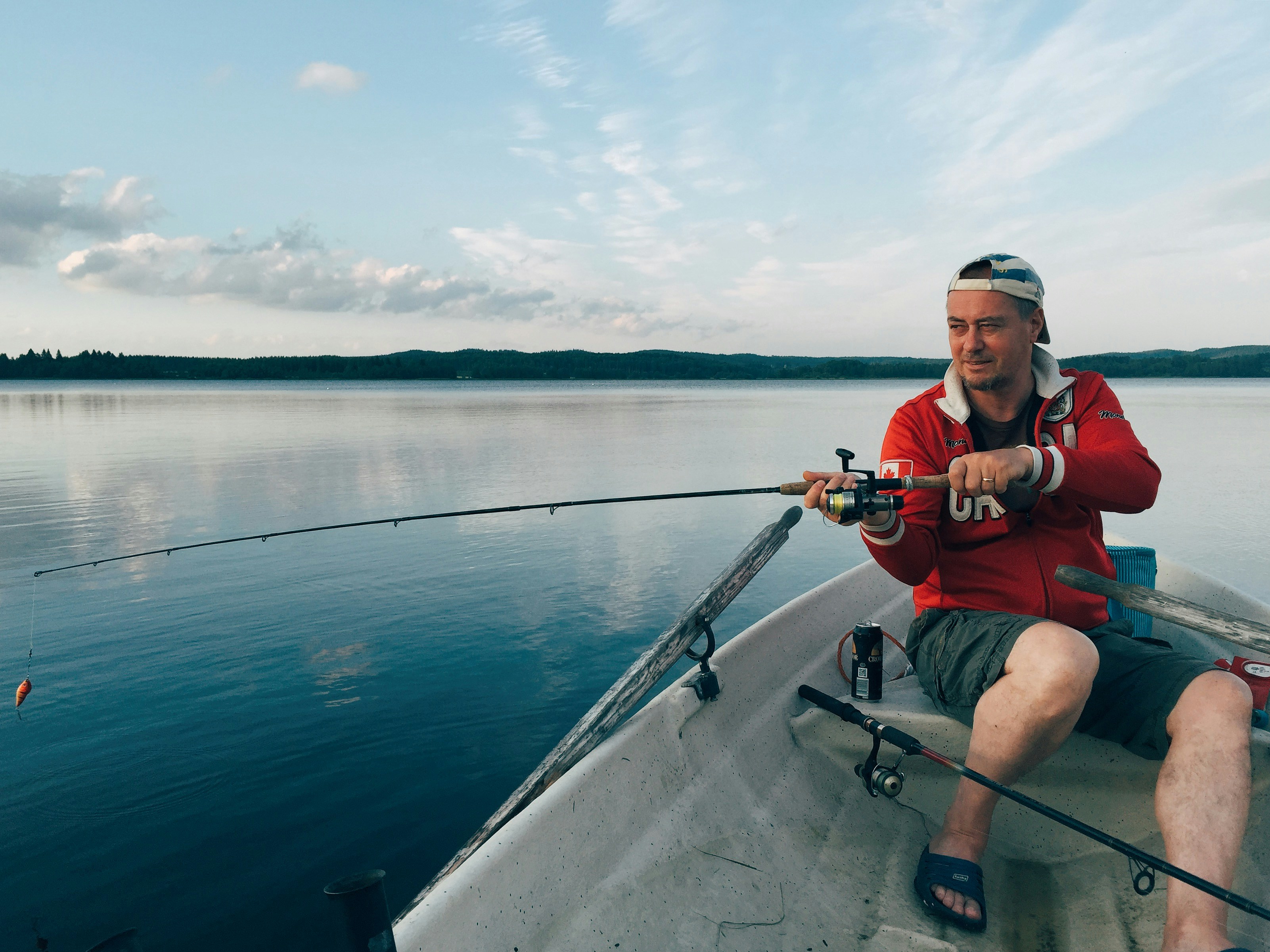 Fisherman in a boat enjoying a peaceful sunset fishing experience on a tranquil lake.