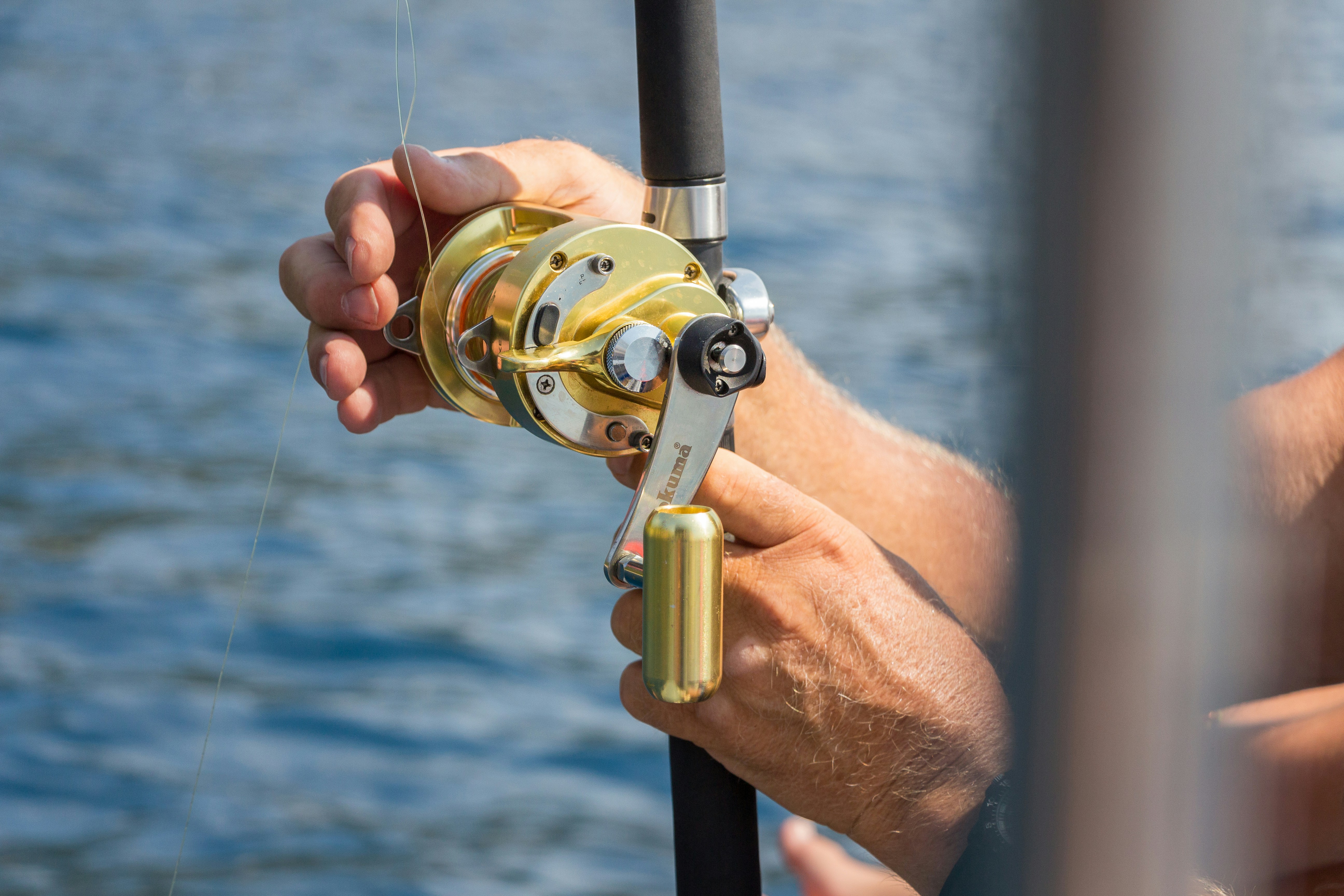 Close-up of a gold fishing reel and skilled angler, showcasing fishing gear and outdoor serenity.