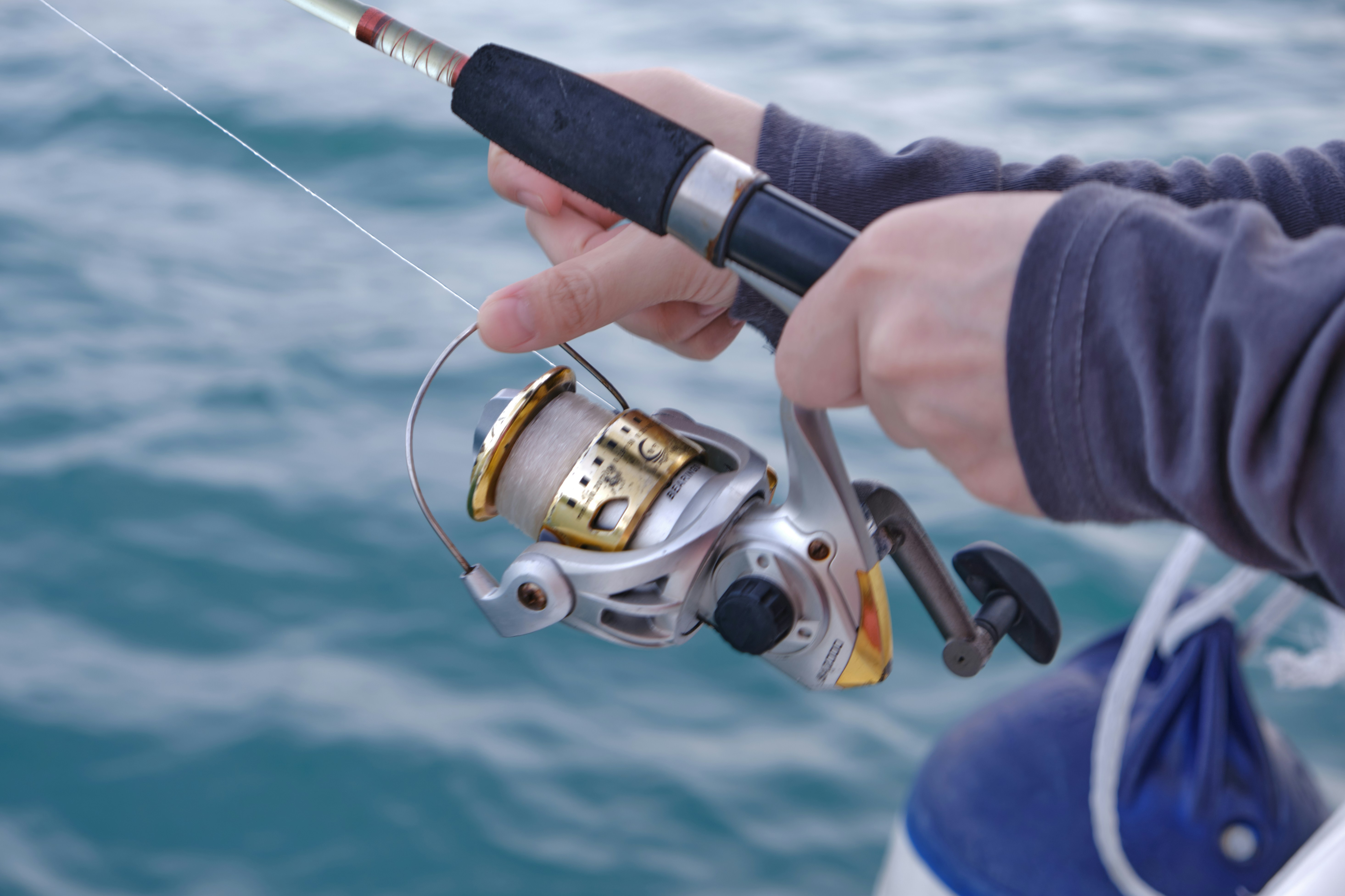 Close-up of fishing rod and reel, showcasing premium fishing gear against serene turquoise water.