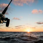 Fishing rod against a stunning sunset over the ocean, perfect for fishing enthusiasts.