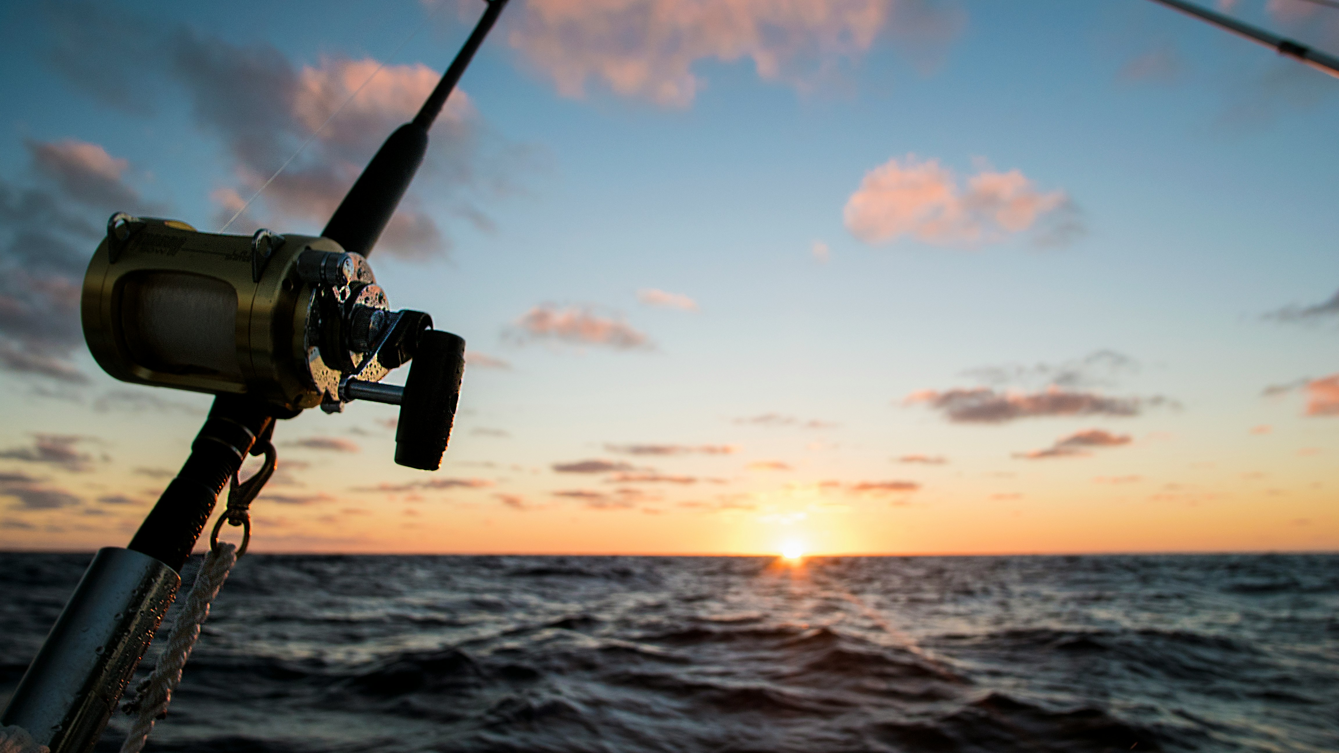 Fishing rod against a stunning sunset over the ocean, perfect for fishing enthusiasts.