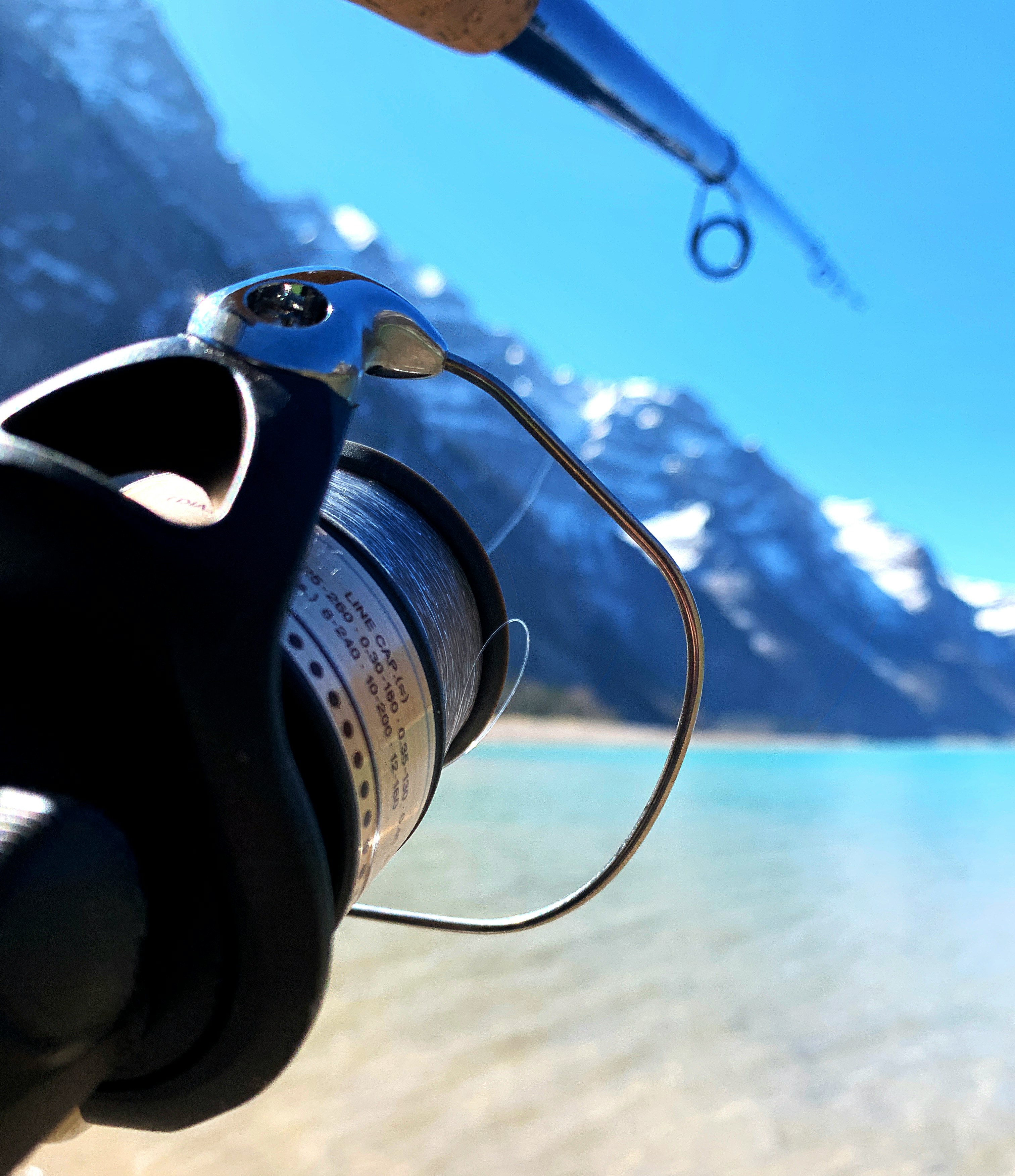 Fishing gear and tranquil lake scenery with mountains, perfect for outdoor enthusiasts.