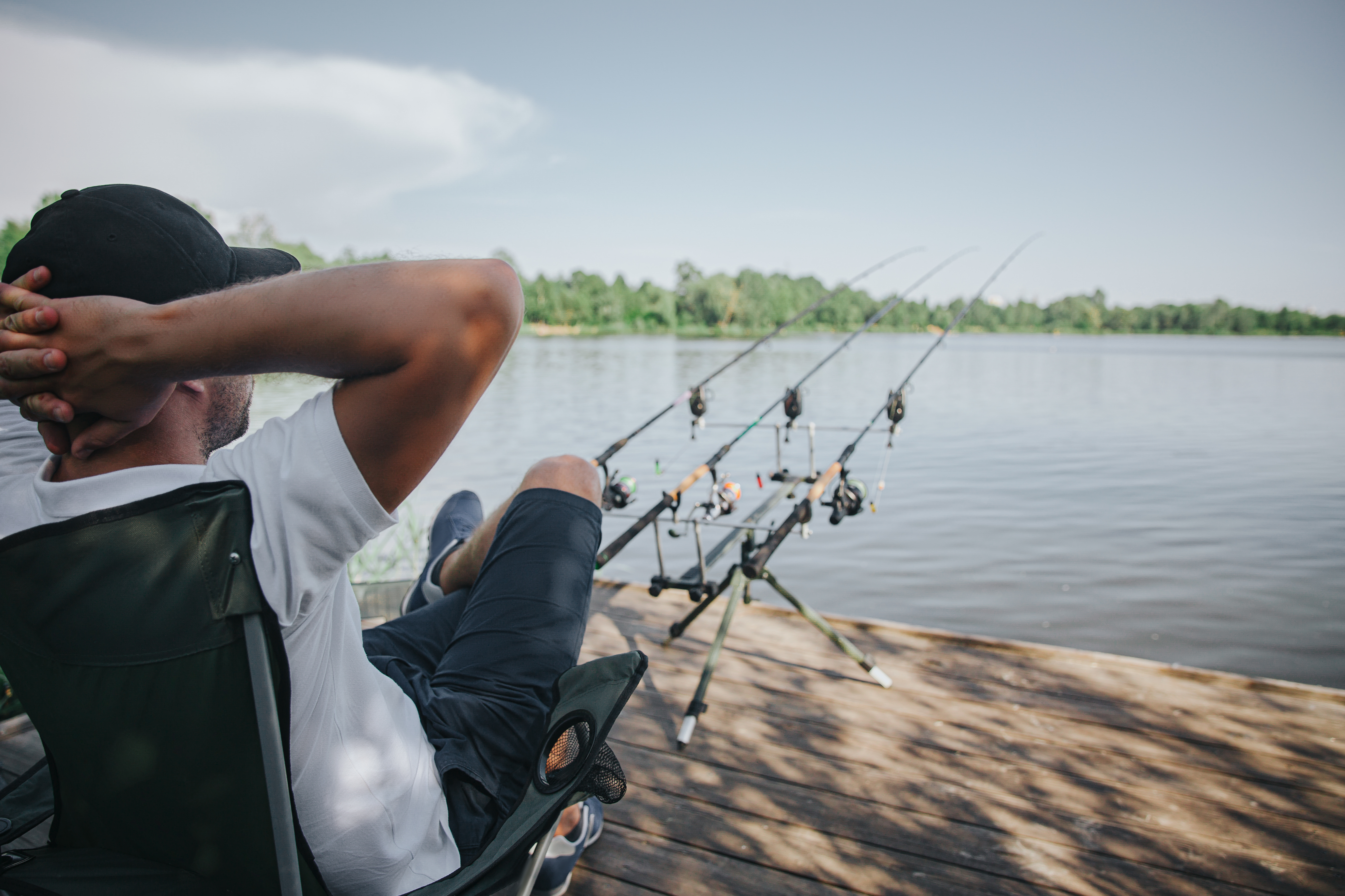 Relaxed fisherman enjoying a sunny day by the lake with fishing rods ready for action.