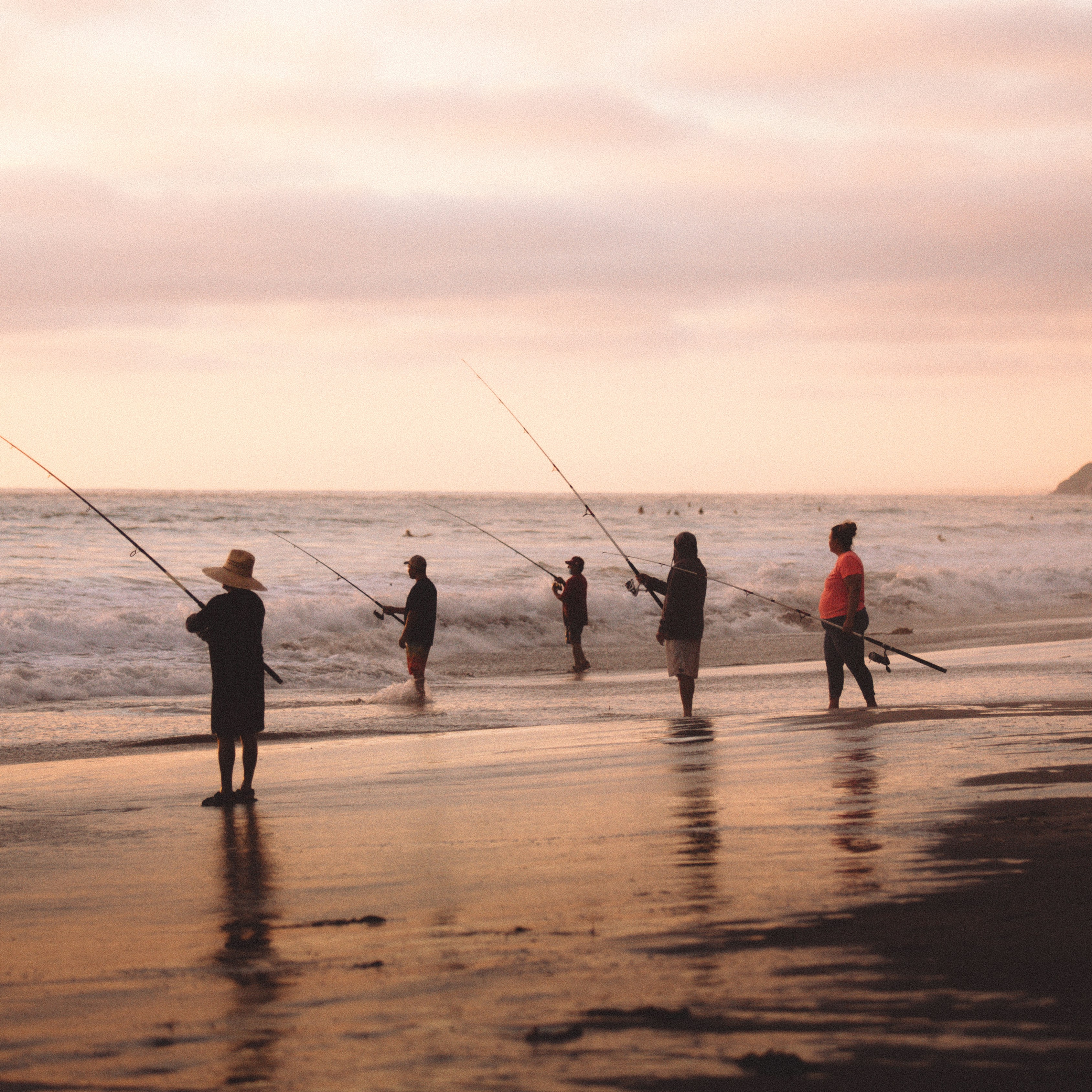 Enjoy fishing at sunset on a tranquil beach with fishing gear and ocean waves.