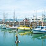 Vibrant harbor scene with colorful boats, fishing gear, and serene turquoise water.