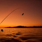 Serene sunset fishing scene with modern gear, perfect for outdoor enthusiasts at the lake.