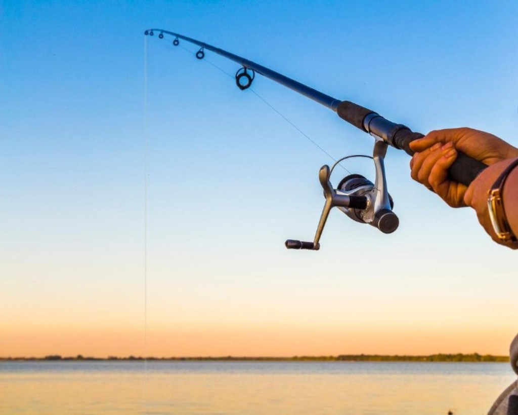 Serene fishing at sunset on a tranquil lake, showcasing beautiful gear and natures peace.