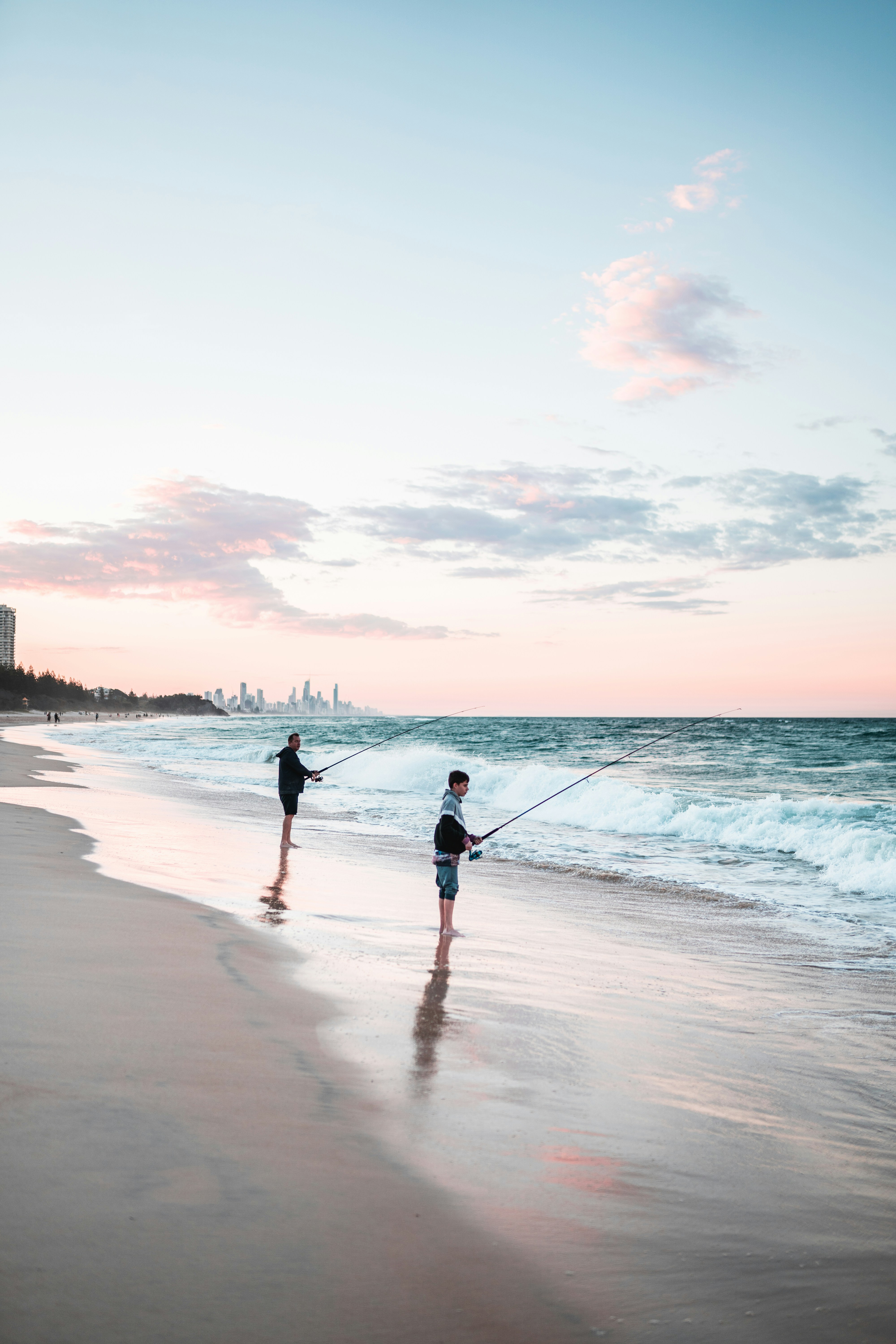 Parent and child fishing at a tranquil beach during sunset, showcasing fishing gear essentials.